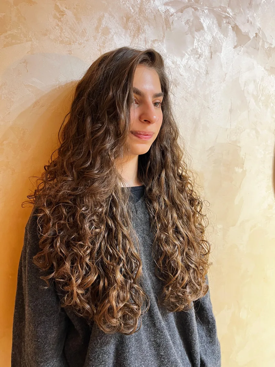 Cliente com cabelo ondulado longo na parede terrosa do ateliê
