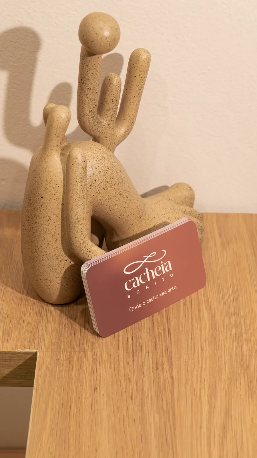 Escultura em cerâmica segurando o cartão do ateliê